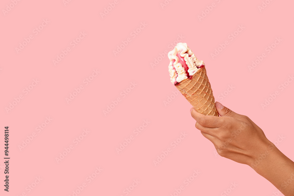 Female hand with sweet ice-cream in waffle cone on pink background Female hand with sweet ice-cream in waffle cone on pink background