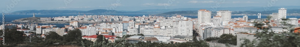 Fototapeta premium A panoramic view of A Coruna, Spain, showcasing the urban landscape with densely packed apartment buildings, the Atlantic Ocean in the background, and the historic Tower of Hercules in the distance