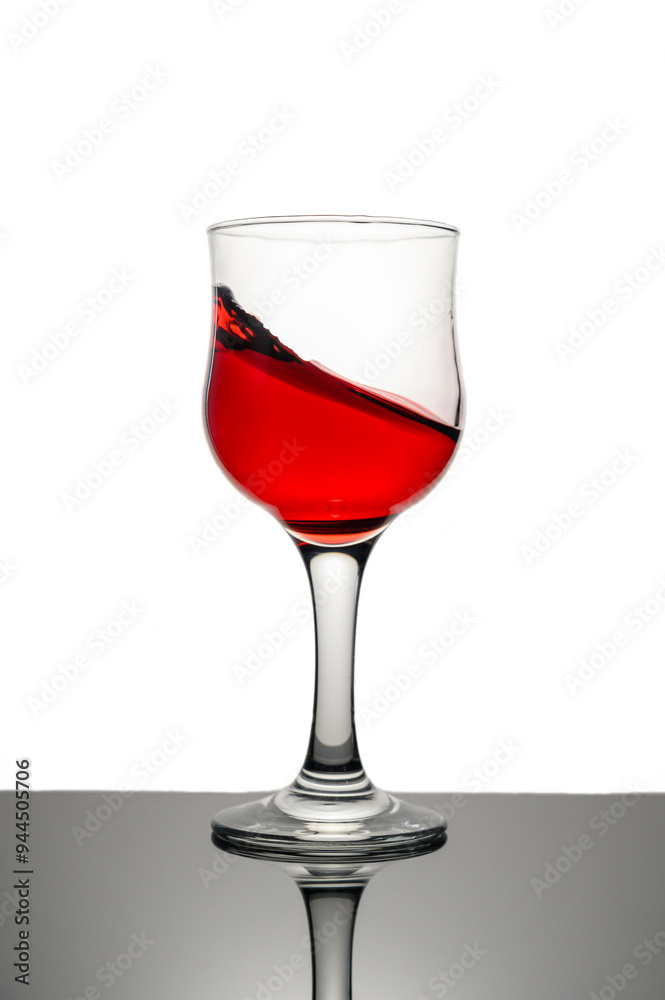 Red wine splashing in glass against white background. Copy space. Red wine splashing in glass against white background. Copy space.