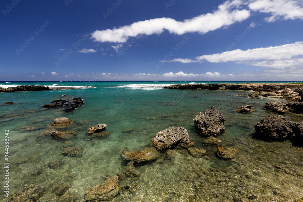 The rocky lava shoreline of The Ponds in Oahu’s Ka’ena Point Beach Park with turquoise ocean, blue skies, and white clouds The rocky lava shoreline of The Ponds in Oahu’s Ka’ena Point Beach Park with turquoise ocean, blue skies, and white clouds