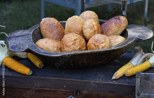Composition of bread products in old wooden dishes and corn on the cob lying next to