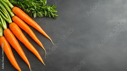 Fresh organic carrots with green tops arranged on a dark background, ideal for healthy food, nutrition, and vegetable-themed concepts.