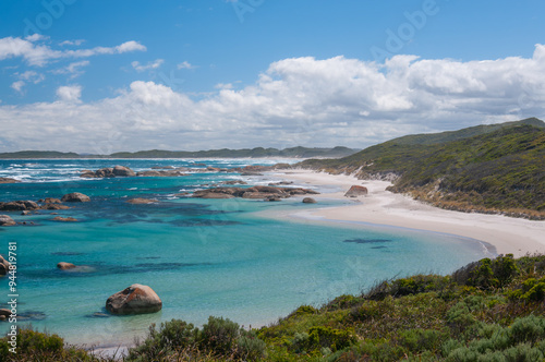 Western Australia, beach near Green's Pool, Denmark, sandy shore with large rocks, clear water, and grassy dunes under a cloudy sky. photo