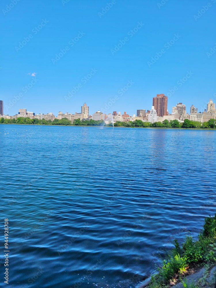 Serene summer view of Central Park lake and Manhattan skyline, New York City Serene summer view of Central Park lake and Manhattan skyline, New York City