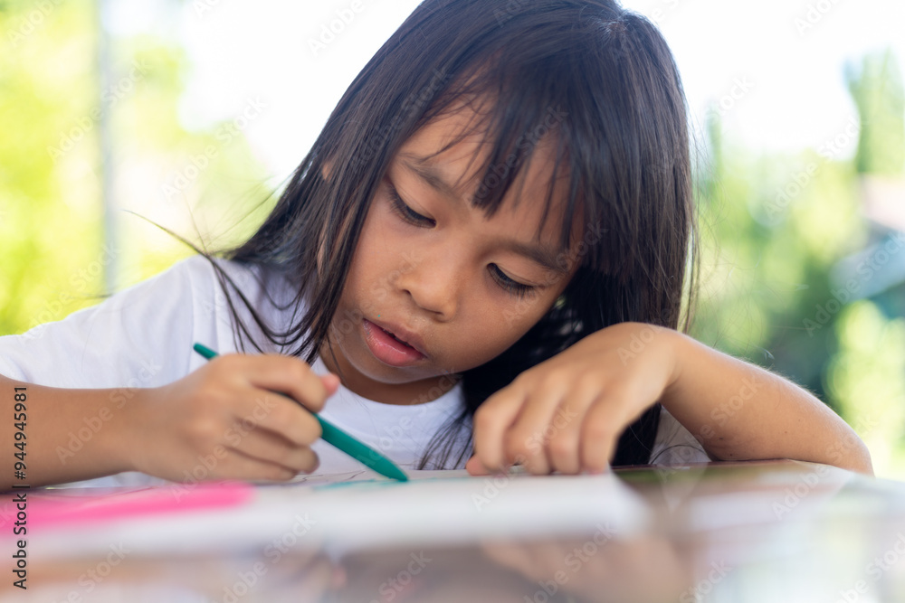 A young girl is drawing on a piece of paper with a marker. A young girl is drawing on a piece of paper with a marker.