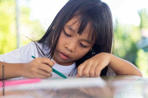 A young girl is drawing on a piece of paper with a marker.