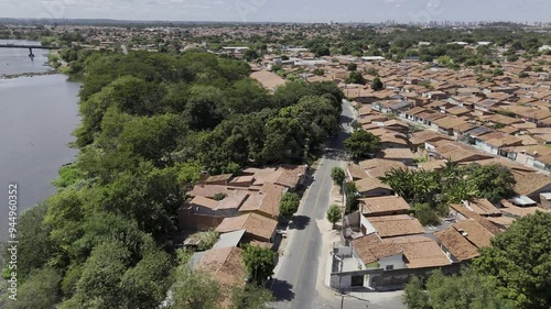 Drone flies over highway next to river approaching houses with red clay roofs in Teresina, Piauí, Brazil photo