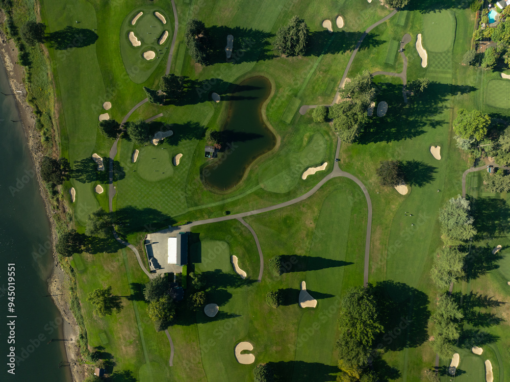 Fototapeta premium A golf course with a pond and a clubhouse