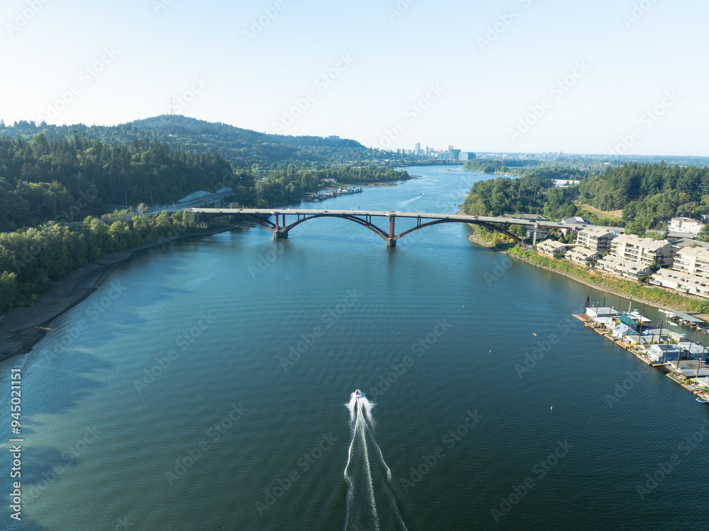 Obraz premium A boat is traveling across a river near a bridge