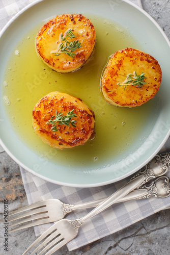 Fondant potatoes or pommes fondante is a slowly roasted the potatoes in butter and stock closeup on the plate on the table. Vertical top view from above photo