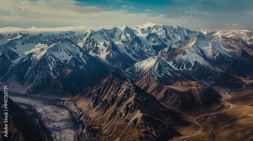 Aerial view of a picturesque mountain range with snow-capped peaks and winding valleys. The scene captures the grandeur