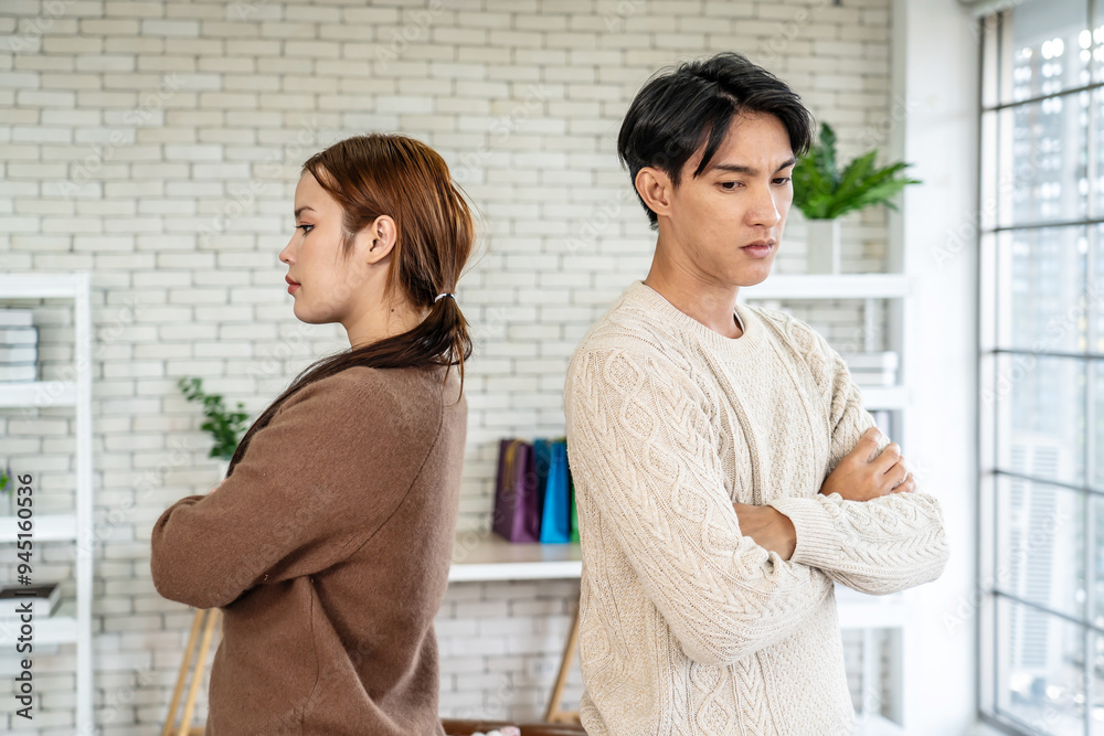 Photo of resentful asian guy and girl acting like arguing couple and not speaking to each other, while standing together in living room at home Photo of resentful asian guy and girl acting like arguing couple and not speaking to each other, while standing together in living room at home