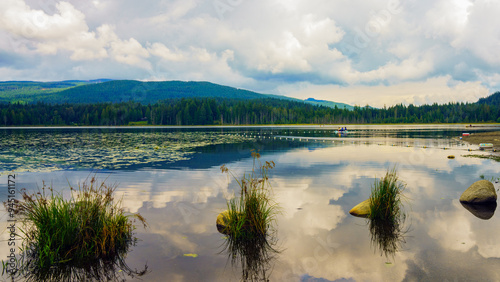 Clouds reflected in tranquil Whonnock Lake, Maple Ridge, BC on a summer day, with mountain and forest backdrop. photo