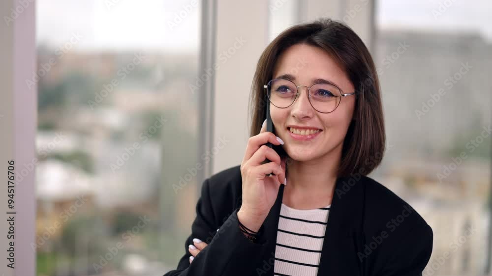 Smiling Caucasian brunette in glasses talks on the phone. Portrait of a business lady having business conversation. Close up. Smiling Caucasian brunette in glasses talks on the phone. Portrait of a business lady having business conversation. Close up.