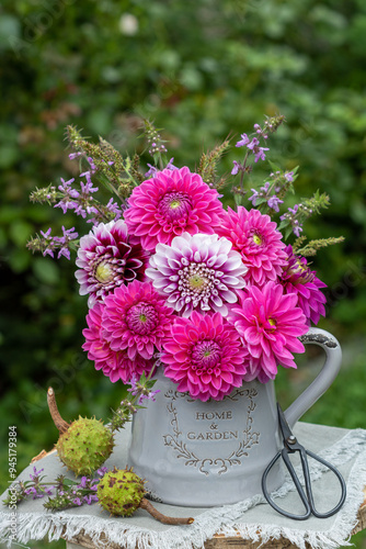 Blumenstrauß mit pink Dahlien, Wiesensalbei und Gräsern im Krug im Garten photo