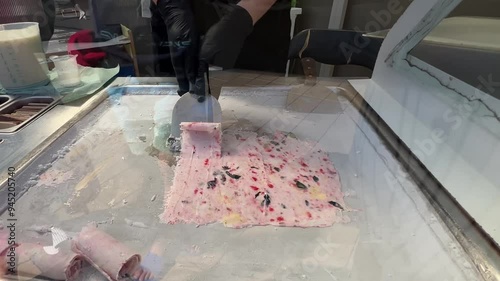 Thai roll ice cream is made by hand in black gloves on the freezer. Sweet dessert made from natural berries and ingredients. The process of making food. The art of cooking Thai ice cream on the street photo