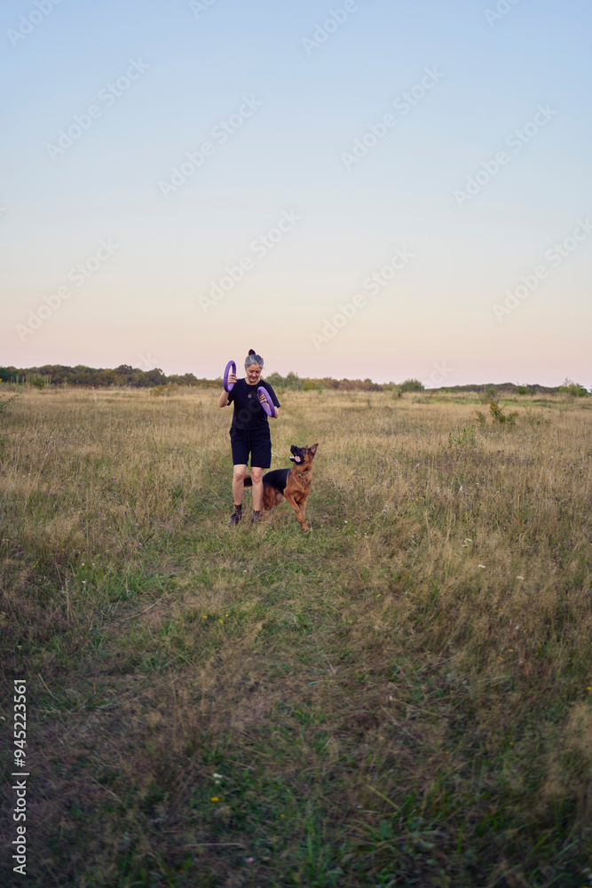 two women play in the field with a german shepherd dog toy at sunset two women play in the field with a german shepherd dog toy at sunset