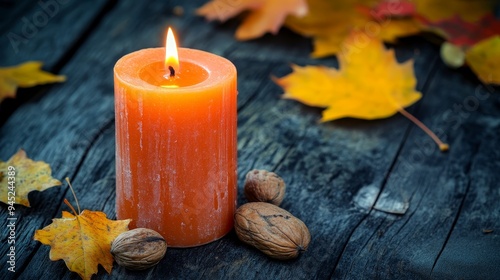 Unscented orange candle on rustic wooden table. Black background with autumn leaves and nuts for decoration and copy space.