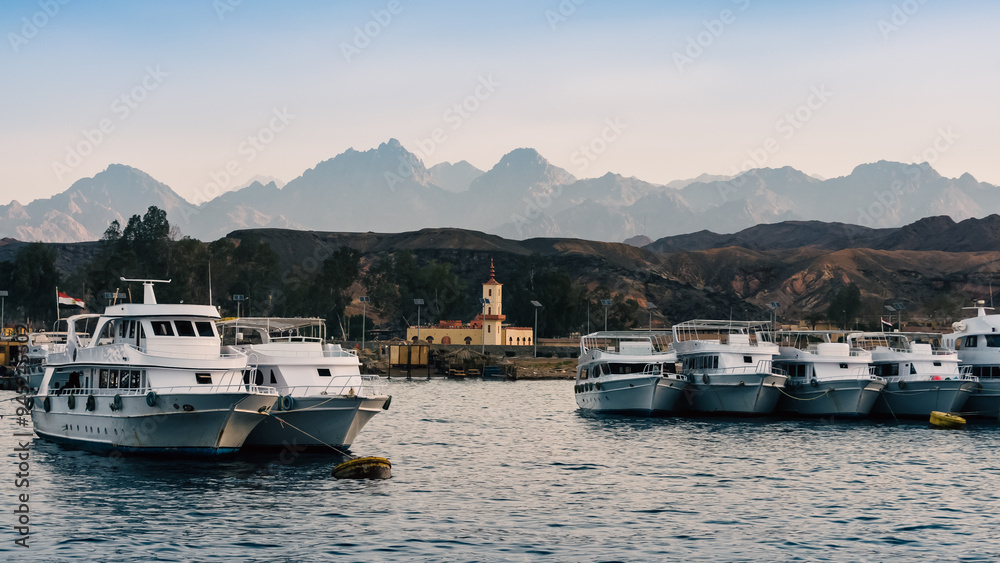 boats standing along the shore in the red sea against the background of mountains and blue sky boats standing along the shore in the red sea against the background of mountains and blue sky