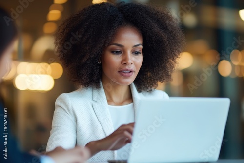 Intense Discussion: African American Businesswoman Engaging with Colleague Over Laptop in Profile View