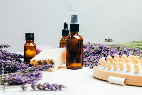 Set of natural cosmetics. Amber bottles with facial, bath liquid on a concrete background with lavender flowers. Front view