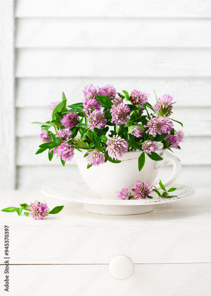 Beautiful bouquet of red clover flowers in a vintage tea cup. Rustic still life with wildflowers. (Trifolium pratense). Selective soft focus. Beautiful bouquet of red clover flowers in a vintage tea cup. Rustic still life with wildflowers. (Trifolium pratense). Selective soft focus.