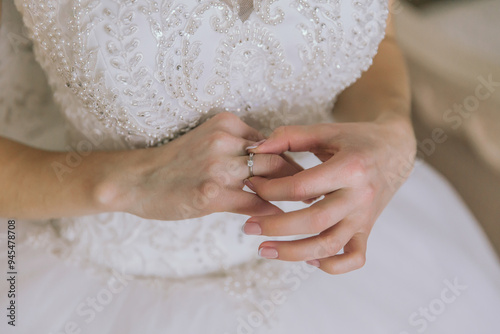 A woman is wearing a wedding dress and holding a ring in her hand. The image has a romantic and intimate mood, as it captures a moment of love and commitment between the couple photo