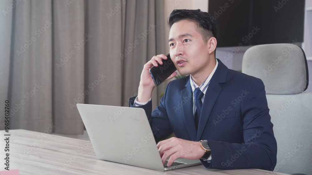 Businessman in suit talking on phone working on laptop. Businessman sitting by the table in cafe with laptop computer. Businessman in suit talking on phone working on laptop. Businessman sitting by the table in cafe with laptop computer.