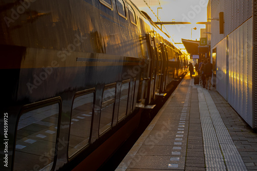Photography Selective focus of the train with blurred people traveling and warm sunlight in the morning as background, Yellow blue bogie and passenger getting in and out the train in public station, Netherlands
