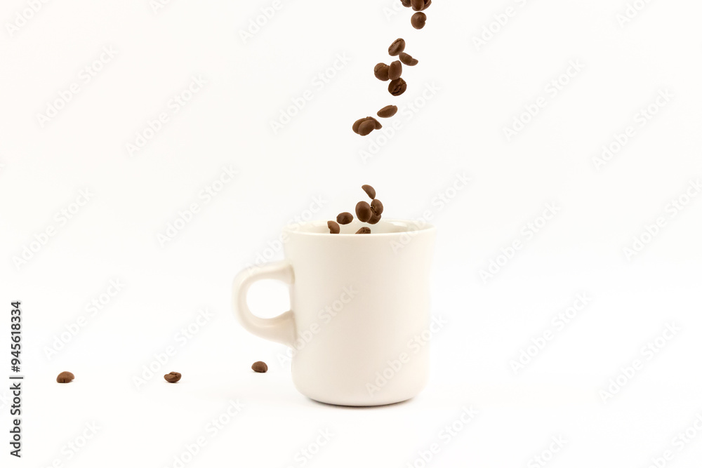 Obraz premium Coffee beans are pouring into a white ceramic cup