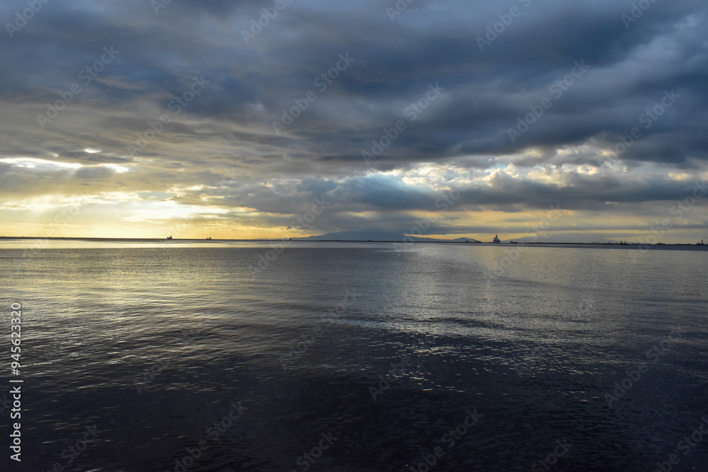 Obraz premium Calm sea meeting a cloudy sky at the horizon during sunset
