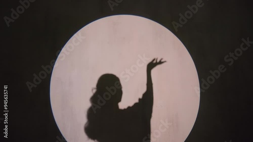 Contrast silhouette of a girl performing oriental dance, arabic elegance, cultural heritage, sense of grace. White moon on black background, unrecognisable model. High quality 4k footage
