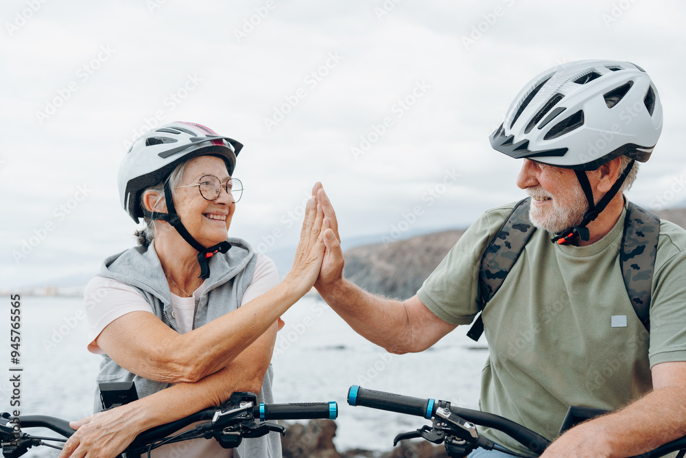Couple of two seniors giving five together outdoors having fun with bicycles enjoying nature. Couple of old people building a healthy and fit lifestyle.. Couple of two seniors giving five together outdoors having fun with bicycles enjoying nature. Couple of old people building a healthy and fit lifestyle..