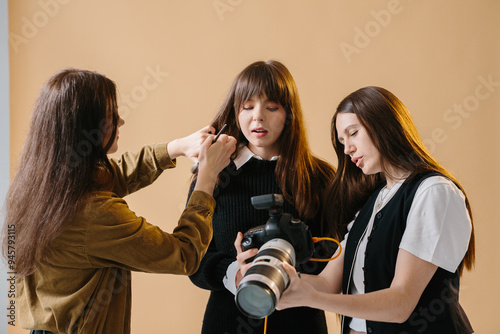 Studio Photoshoot Backstage: Makeup Artist Preps Female Model as Photographer Reviews Images