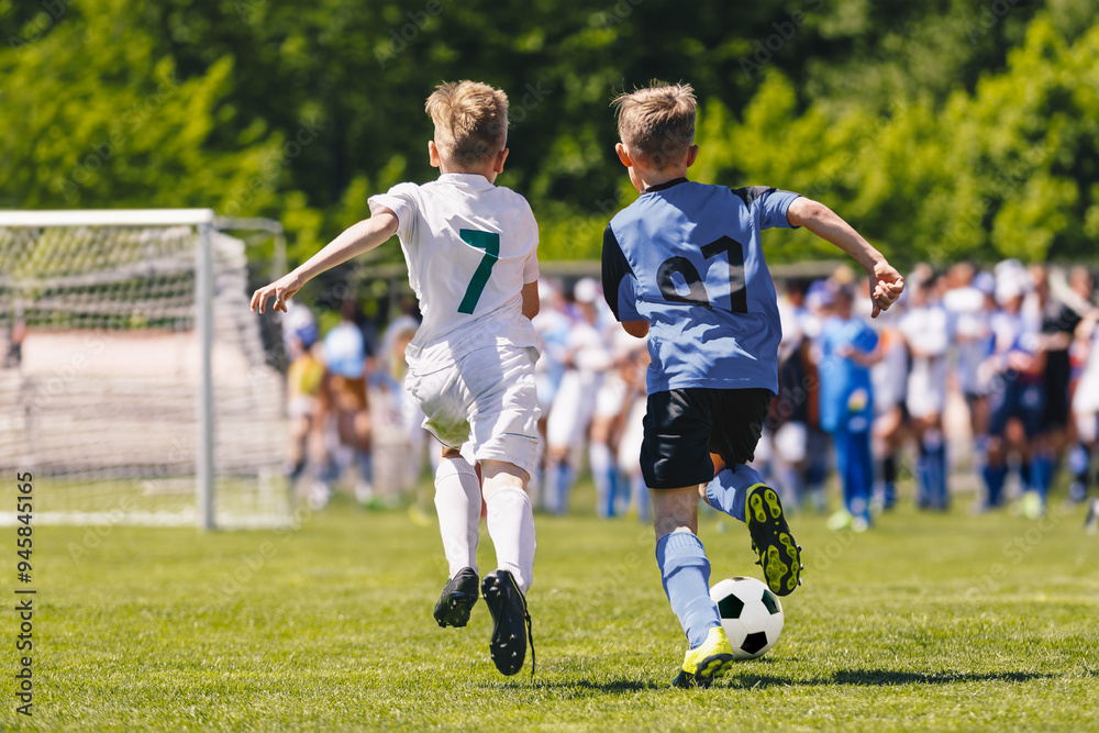 Obraz premium Young Boys Running After the Ball During a Soccer Game. Little Boys, Kids in Sports Uniforms Play With Ball at the Soccer School Stadium. Young Boys Compete in Tournament Match in a Duel