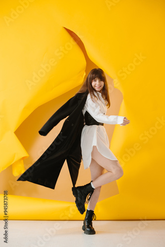 Fashion photo of young pretty girl in stylish clothes posing on torn paper background.