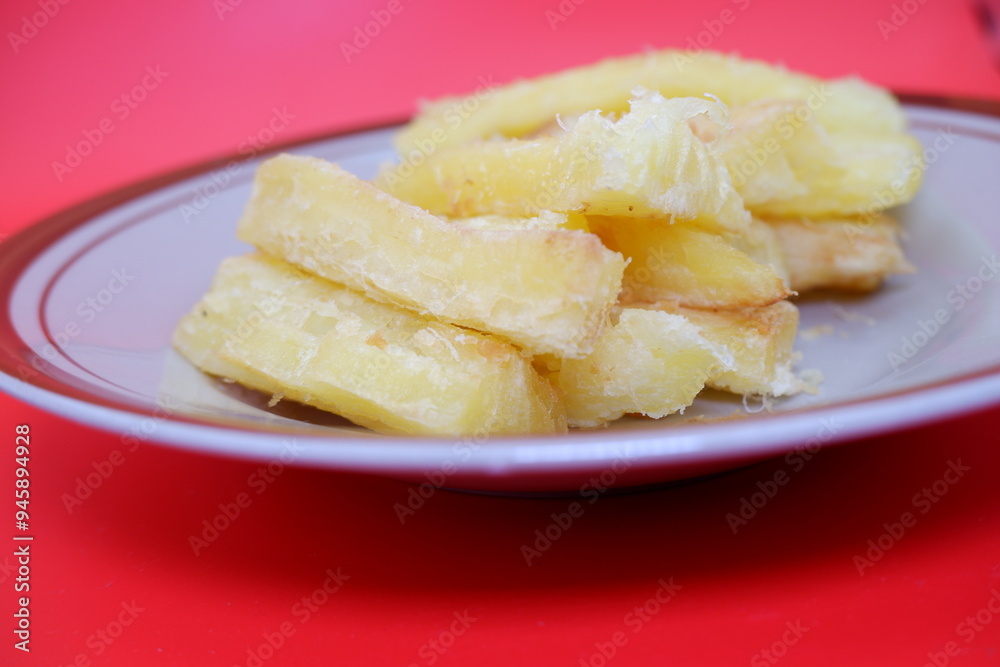 Fried cassava served on a plate. Fried cassava dish isolated on a red background. Fried cassava served on a plate. Fried cassava dish isolated on a red background.