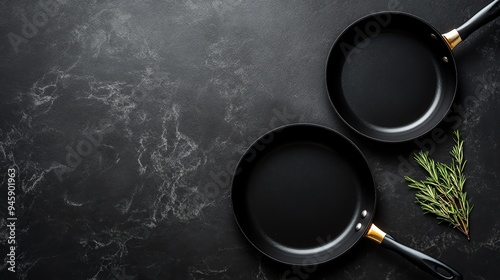 Two black frying pans on a dark countertop, ideal for cooking and kitchen decor. Perfect for culinary and food-related themes.