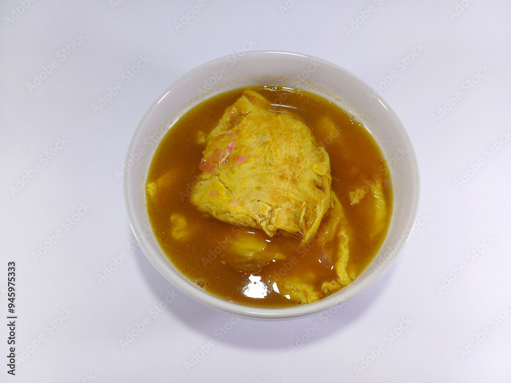 Tello cempa, a traditional Bugis dish featuring processed eggs as a plain omelette, served in a spicy and sour tamarind soup, all presented in a white bowl against a clean white background Tello cempa, a traditional Bugis dish featuring processed eggs as a plain omelette, served in a spicy and sour tamarind soup, all presented in a white bowl against a clean white background