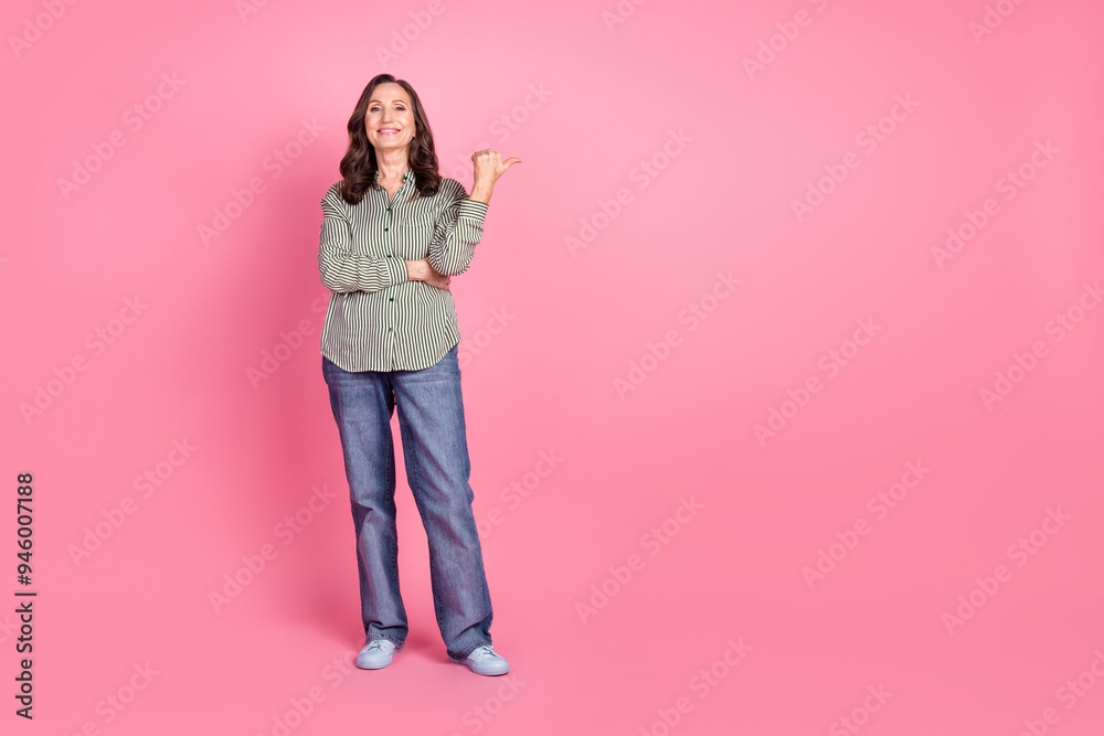 Full length photo of adorable lovely woman wear striped shirt showing thumb empty space isolated pink color background Full length photo of adorable lovely woman wear striped shirt showing thumb empty space isolated pink color background
