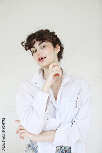 Young female model in jeans and white shirt posing on white background.