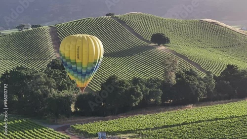 Aerial view of picturesque vineyard and rolling hills with a hot air balloon in the sky, location unknown, United States.