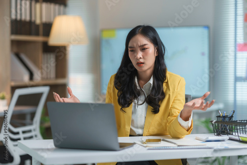 Frustrated businesswoman in office, dealing with laptop connection problems, stressed and overwhelmed by looming deadline, visibly upset and annoyed, trying to resolve issues photo