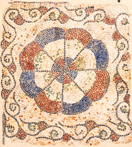 Decorative ancient mosaic representing a colorful circle inside a square decorated with floral motifs
