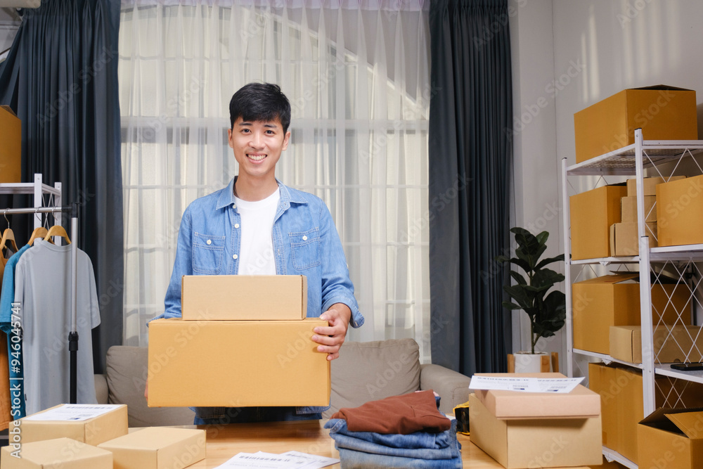 Portrait of a confident young online entrepreneur working from his home office, surrounded by clothing products and shipping boxes. Portrait of a confident young online entrepreneur working from his home office, surrounded by clothing products and shipping boxes.