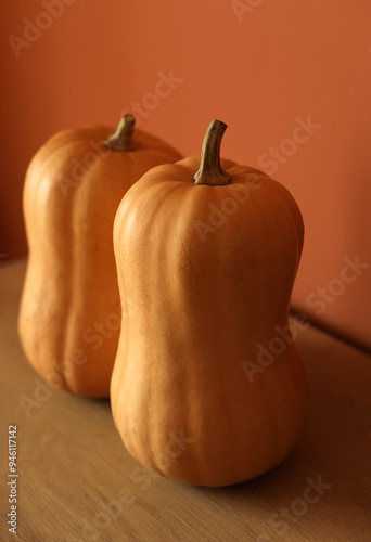 two orange pumpkins on a wooden table and an orange background, autumn, background banner, pumpkin Thanksgiving Halloween autumn park garden harvest vegetables seasonal holiday, home decoration, agric photo