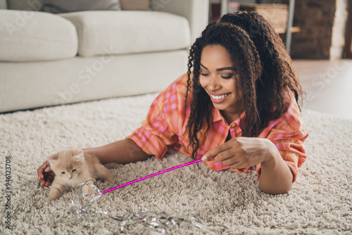 Photo of cheerful shiny lady wear plaid shirt lying foor enjoying play kitten teasing stick indoors room home house photo