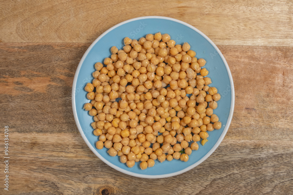Chickpeas on blue ceramic plate over wooden background.
Chickpeas on blue ceramic plate over wooden background.