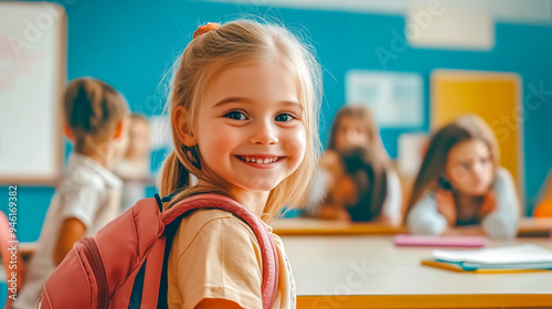 Niña con mochila en su primer día de la vuelta al cole sentada en su pupitre de clase