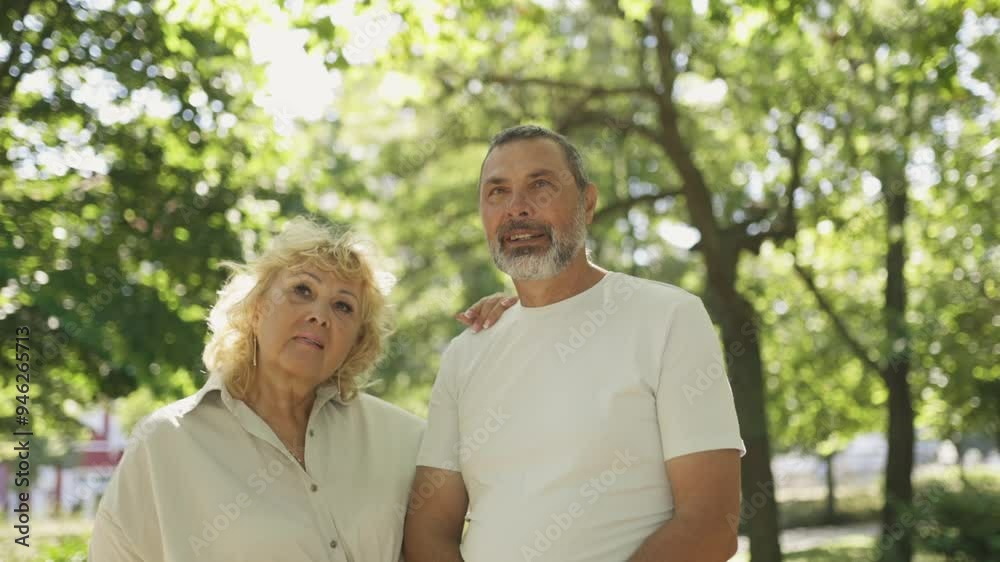 Joyful senior couple posing together in a lush park setting Joyful senior couple posing together in a lush park setting
